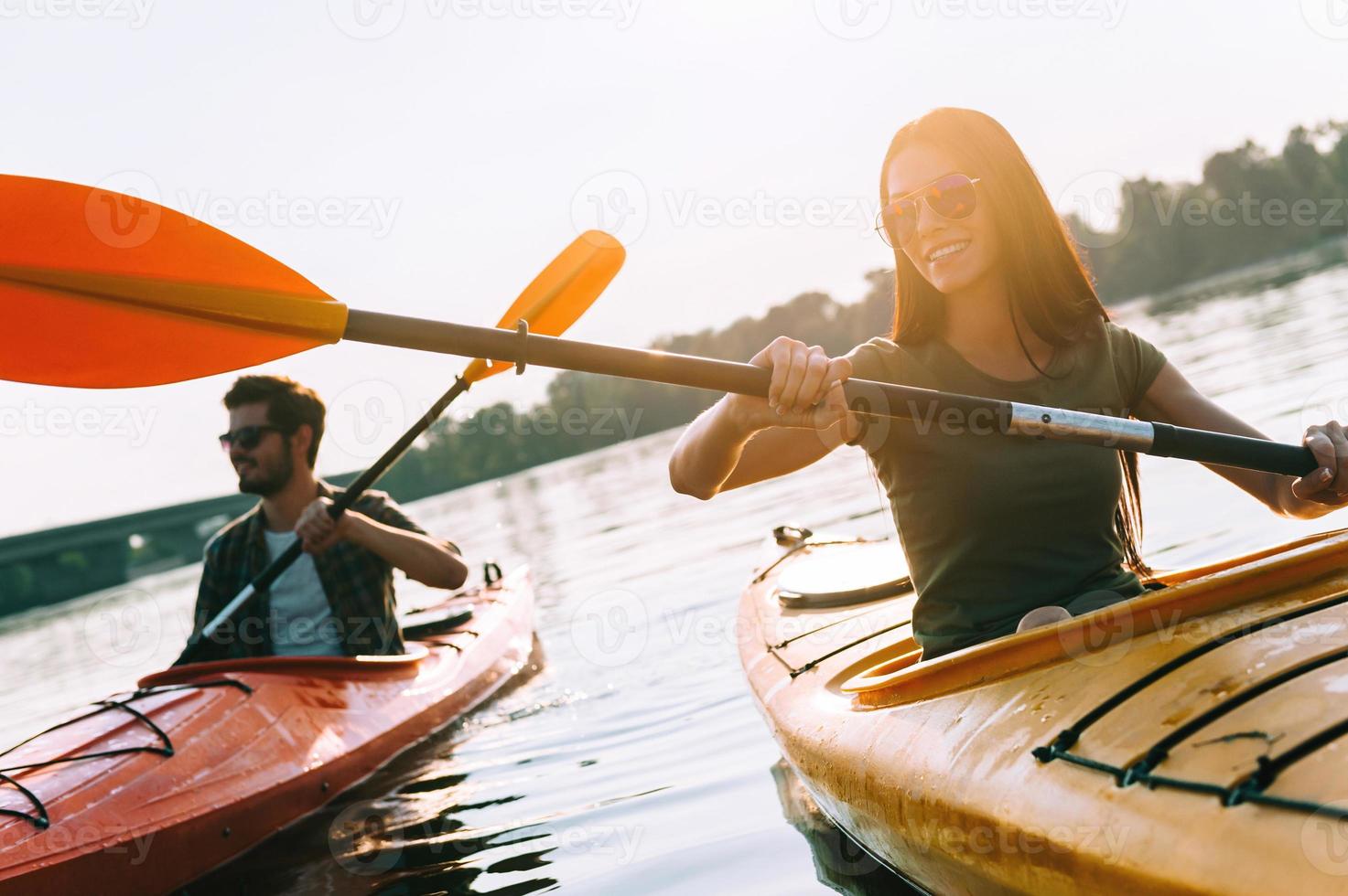 Enjoying nice day on river. Beautiful young couple kayaking on lake together and smiling photo