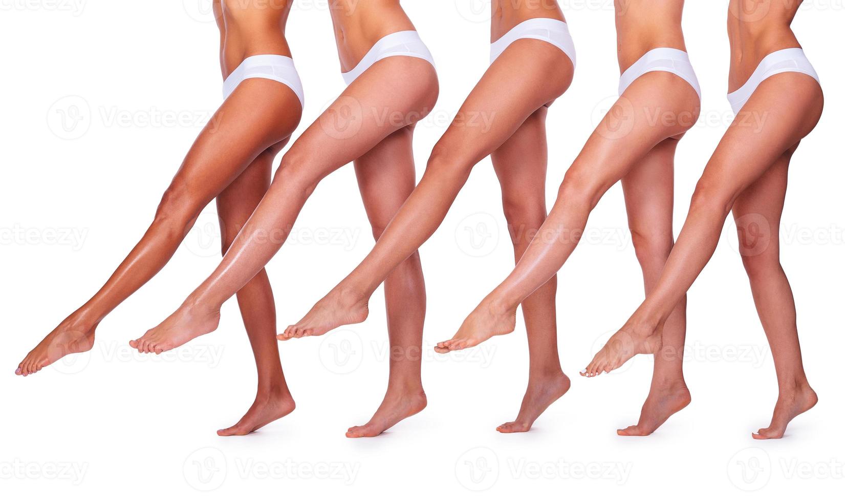 Slender and perfect. Close-up of five beautiful women in white panties stretching out their perfect legs while standing close to each other and against white background photo