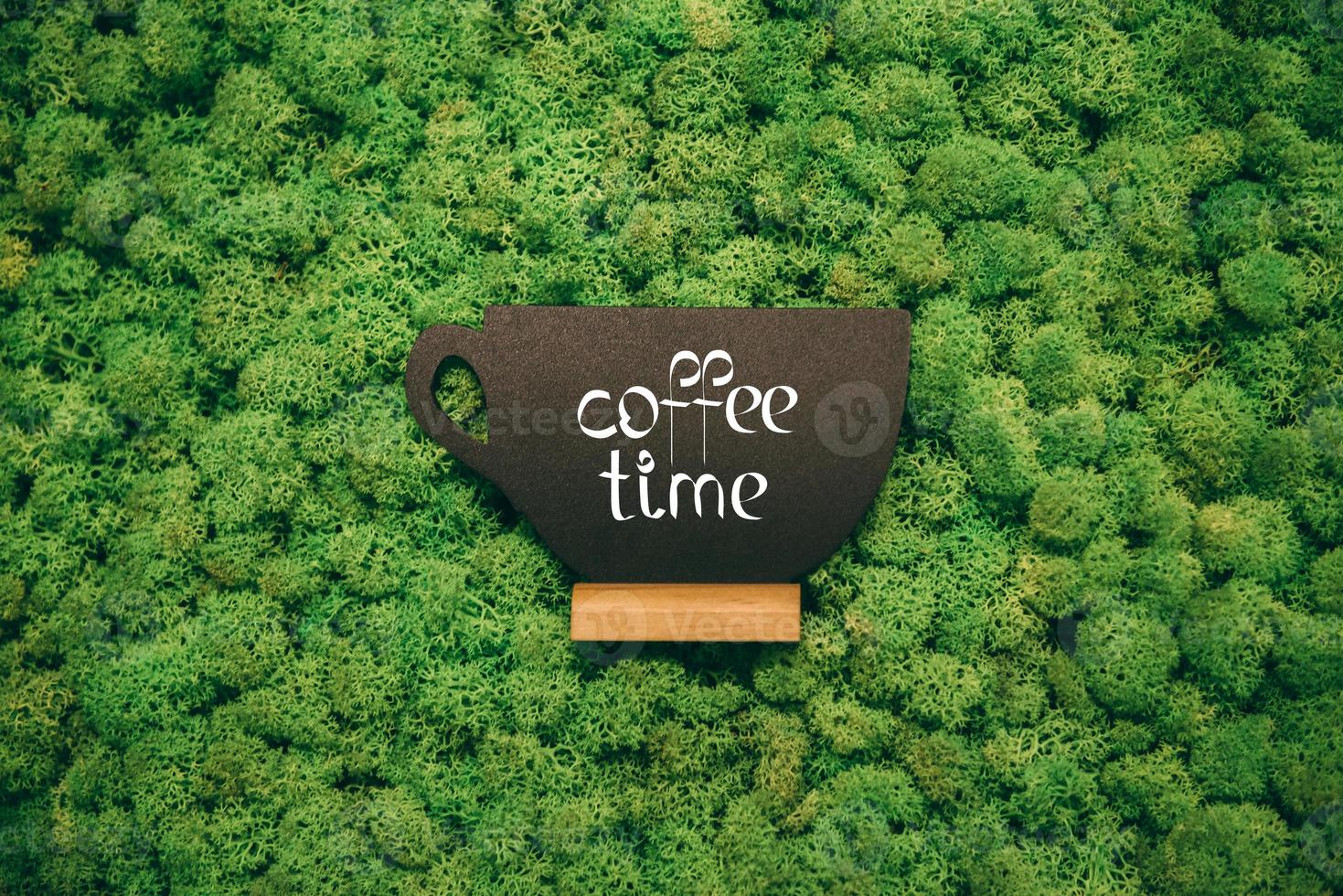 Coffee time. Cup shaped blackboard with hand writing text at moss background photo