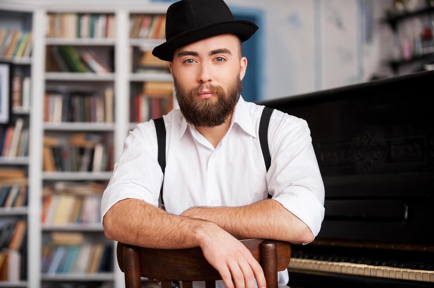 Waiting for inspiration. Portrait of handsome young bearded men sitting in front of his piano photo