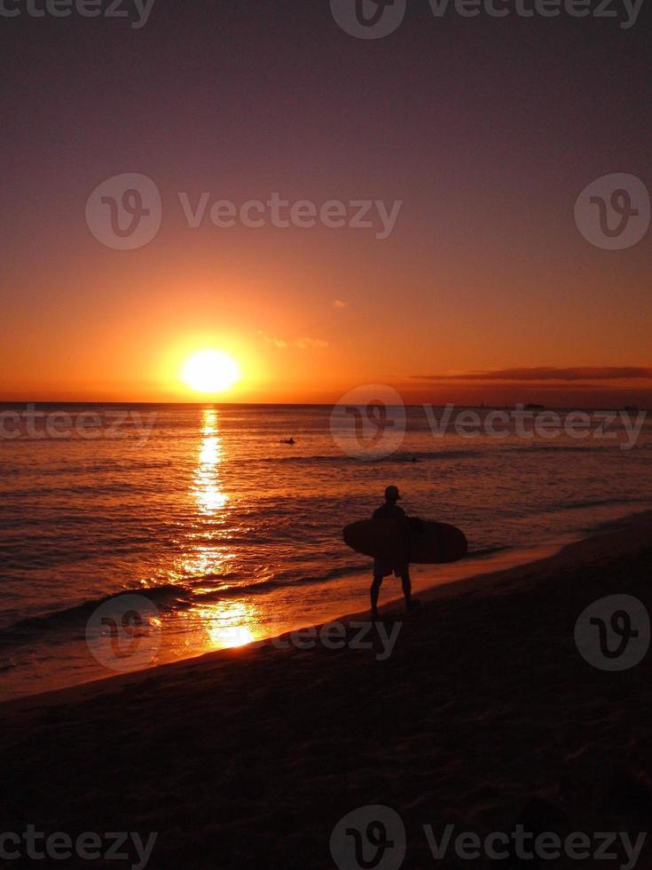 Silhouette of a surfer at sunset photo