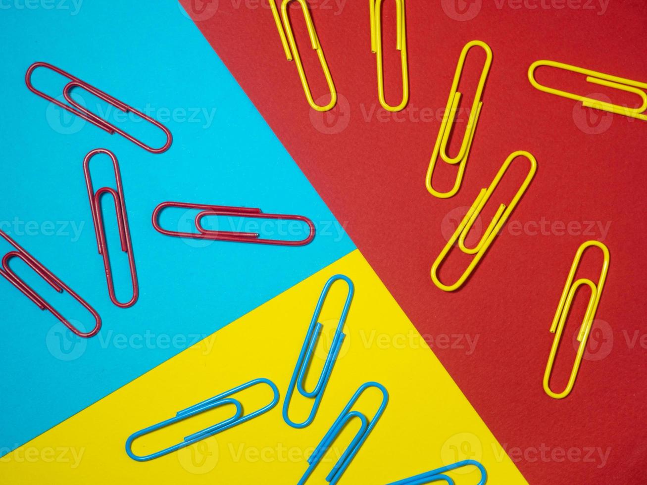Colored paper clips on paper. Office supplies.  Colorful office supplies. photo