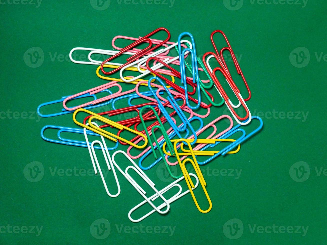 Colored paper clips on paper. Office supplies. Business goods. photo