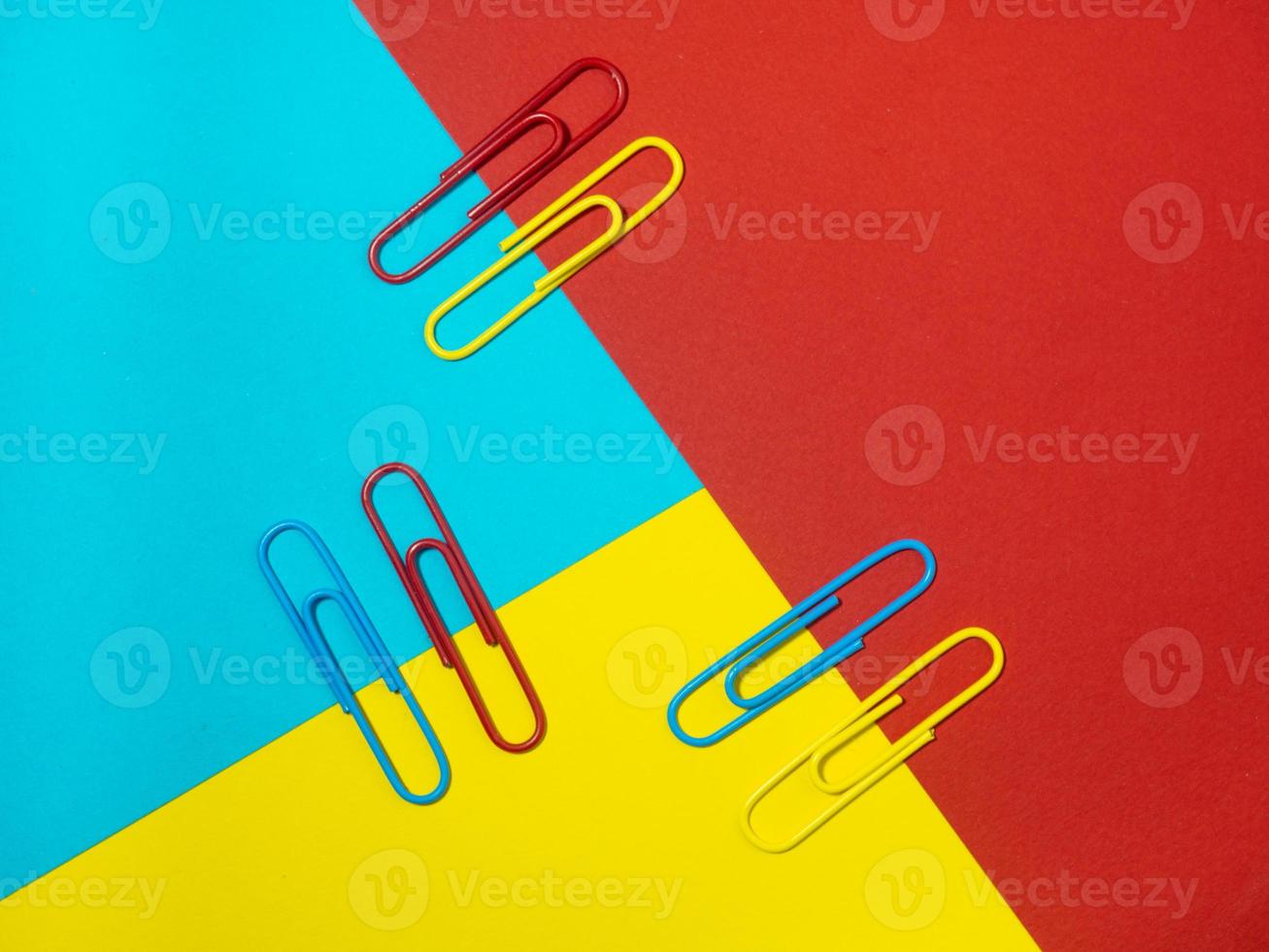 Colored paper clips on paper. Office supplies.  Colorful office supplies. photo