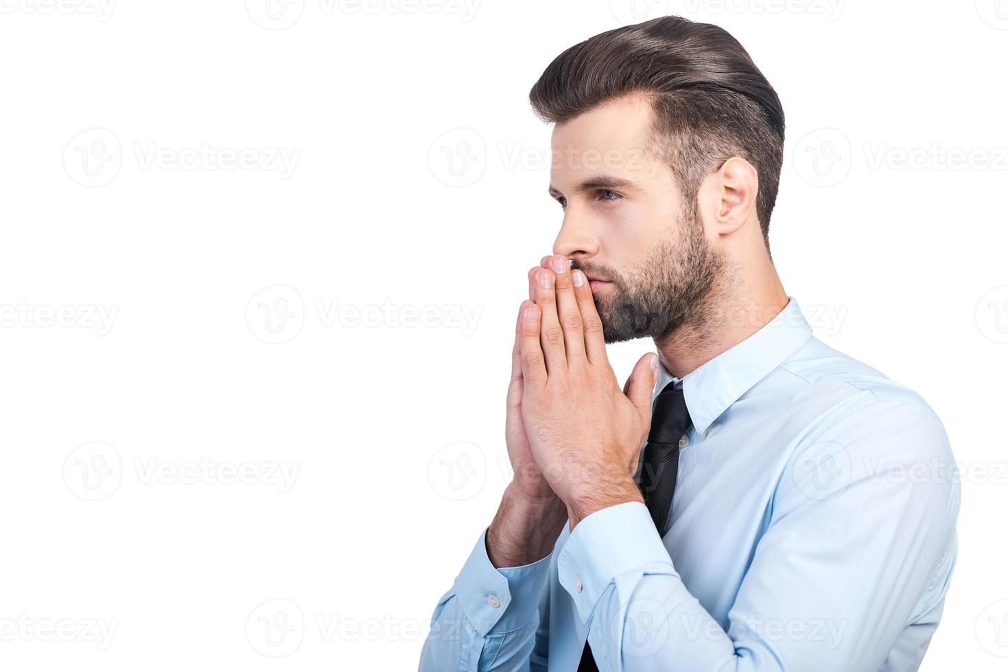 Thinking about future. Side view of thoughtful young handsome man in shirt and tie holding hand on chin and looking away while standing against white background photo