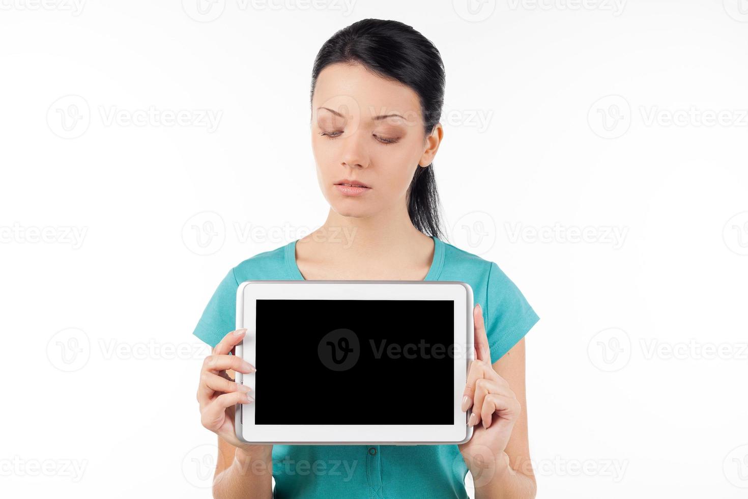 Woman with digital tablet. Confident young woman holding digital tablet and looking at it while isolated on white photo