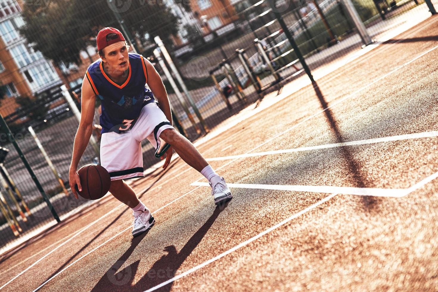 verdadero ganador toda la longitud de un joven con ropa deportiva jugando baloncesto mientras pasa tiempo al aire libre foto