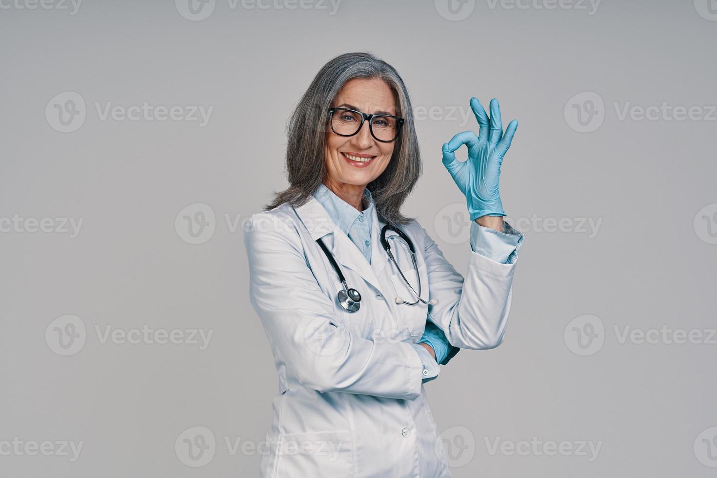 Mature beautiful female doctor putting on surgical gloves and smiling photo