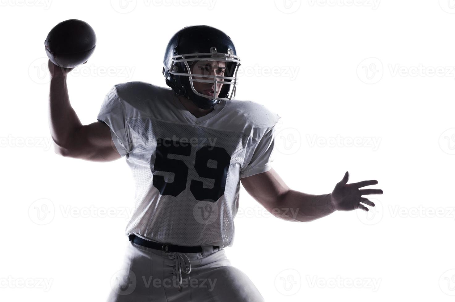 Decisive shot.  American football player throwing ball standing against white background photo