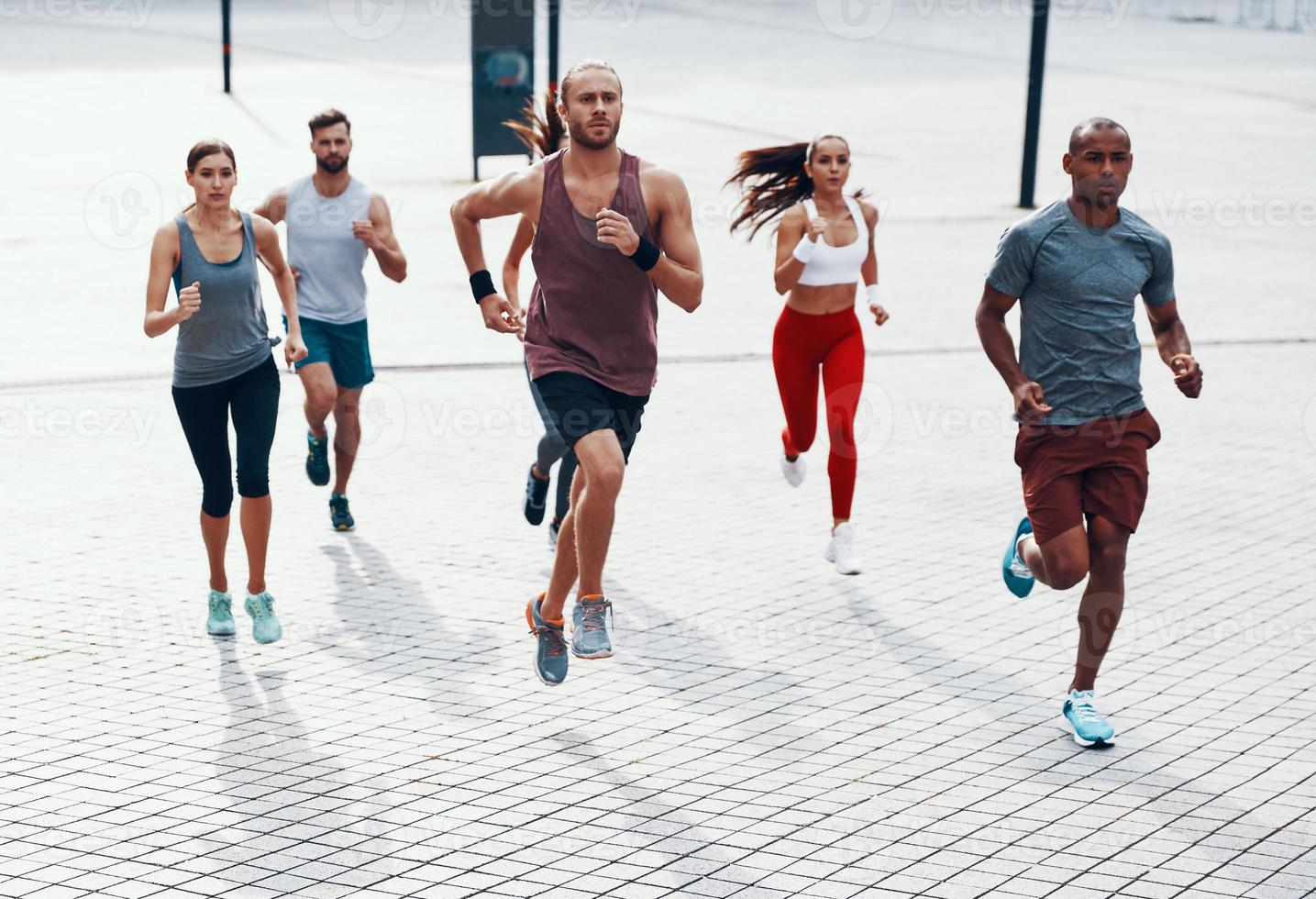 toda la longitud de la gente con ropa deportiva trotando mientras hace ejercicio en la acera al aire libre foto