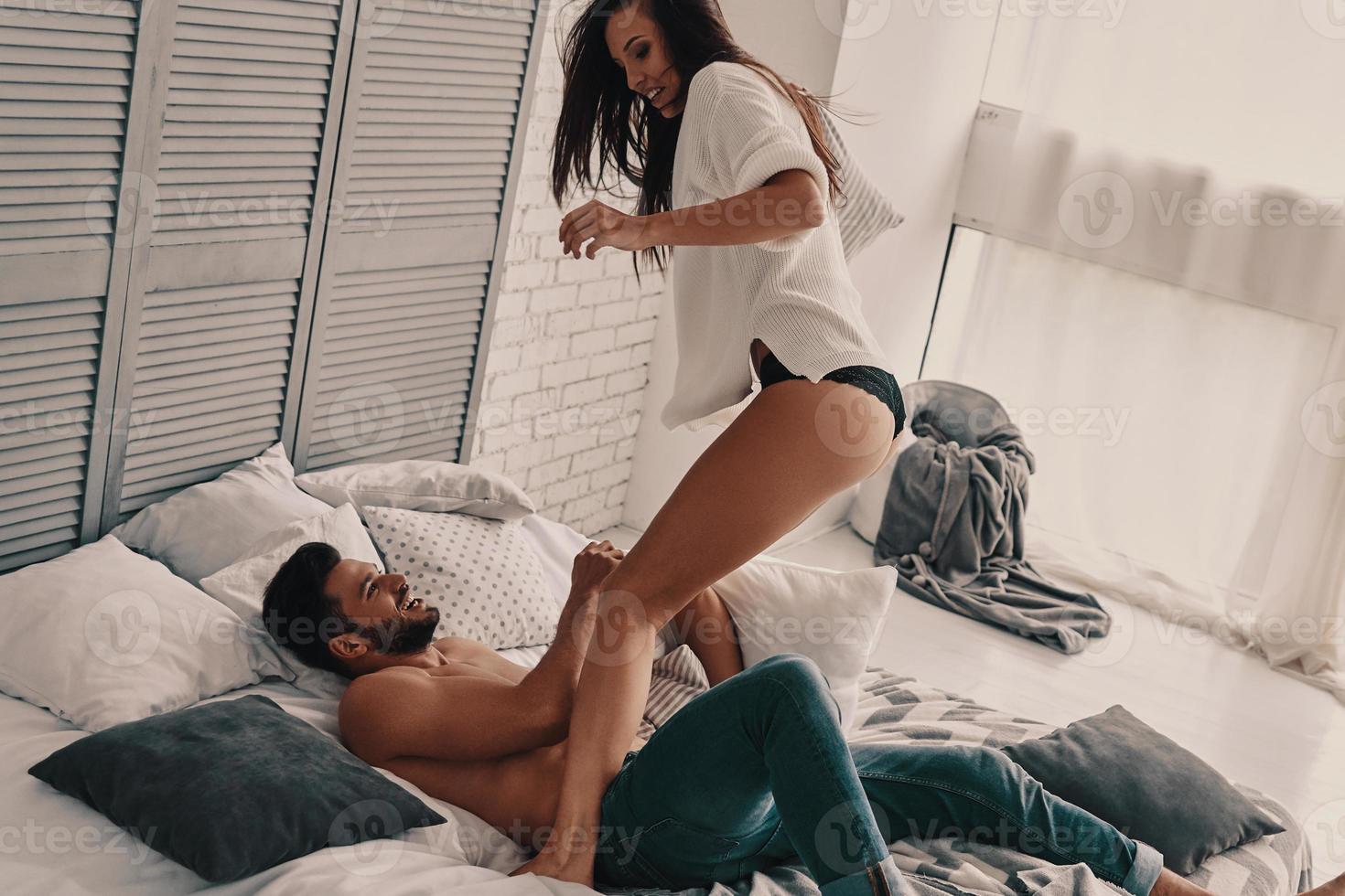 Always happy together. Happy young couple having a fun pillow fight while spending carefree time in the bedroom photo