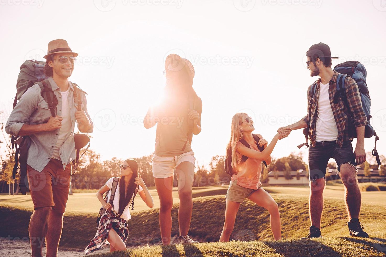 Discovering new places. Beautiful young people with backpacks walking together and looking happy photo