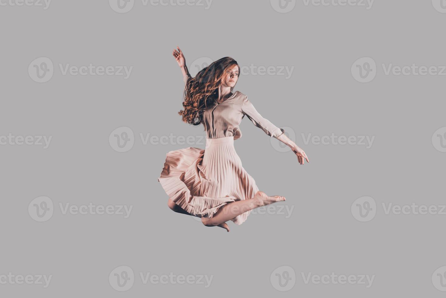 Beauty in the air. Studio shot of attractive young woman hovering in air photo