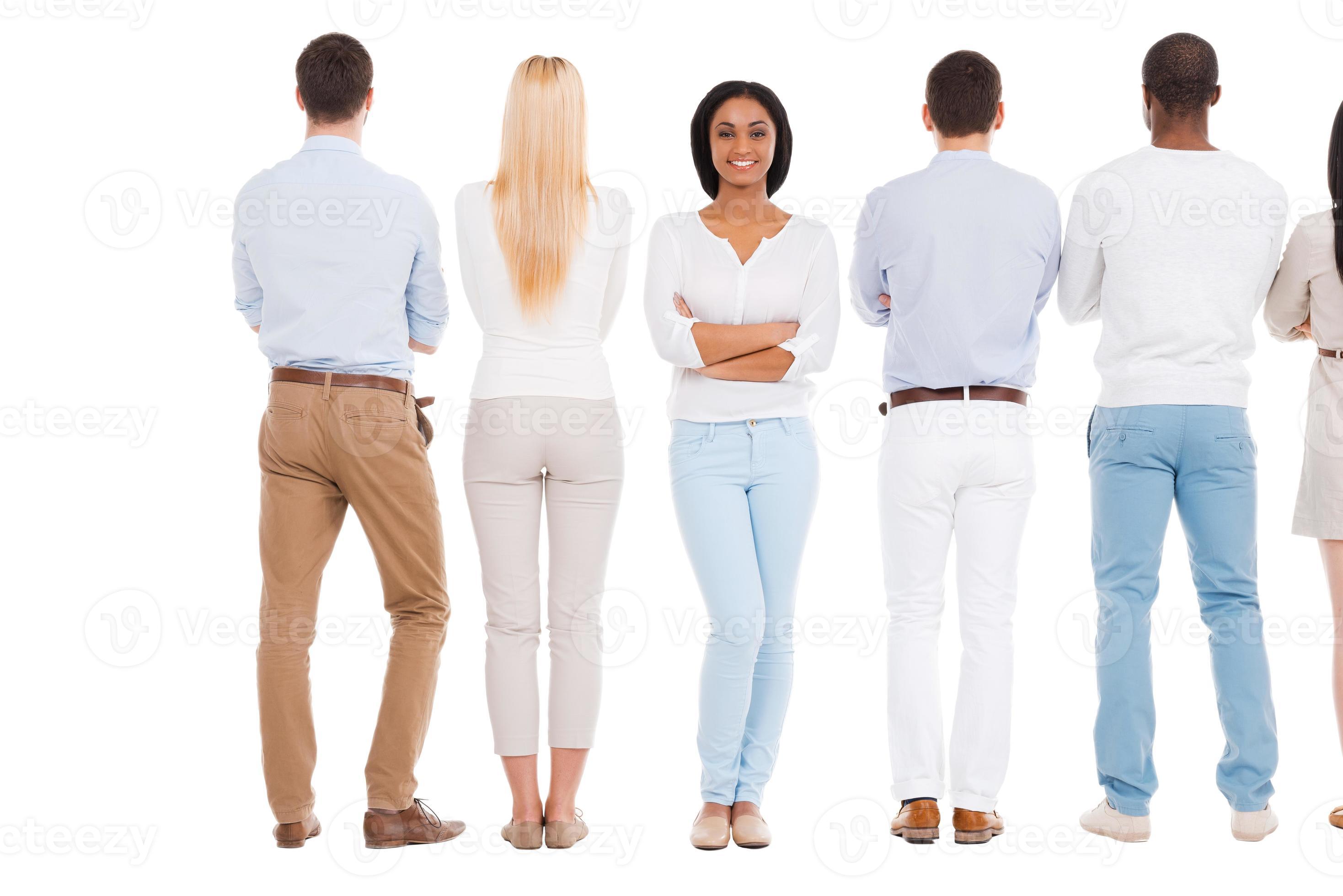 Now it is my turn. Rear view of group of people standing in a row and  against white background while one beautiful African woman standing face to  camera and smiling 13572035 Stock