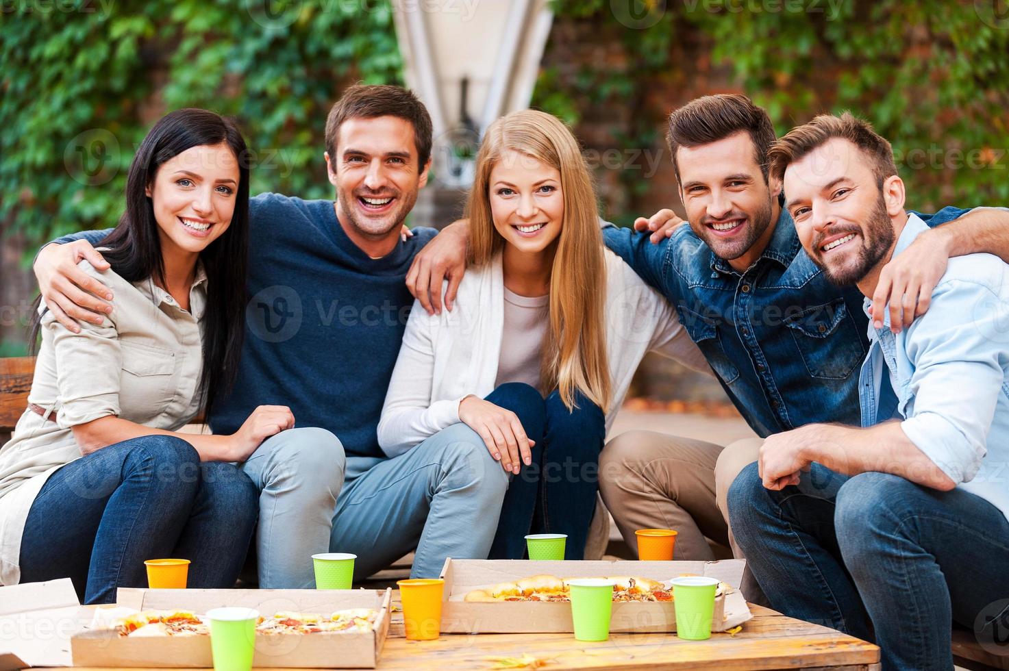The best friends ever Group of joyful young people bonding to each other and looking at camera while having good time together photo