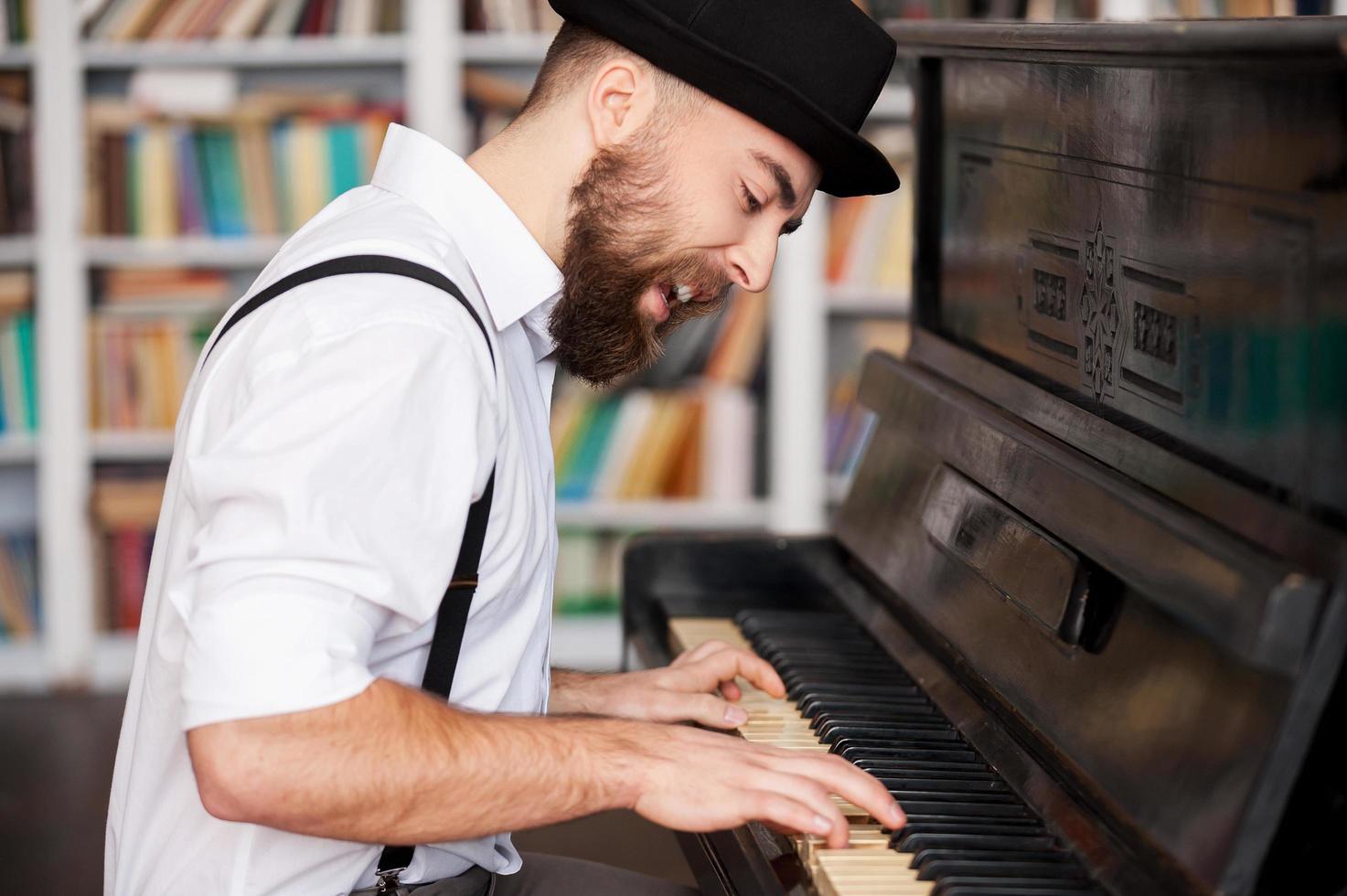 He got creative soul. Handsome young bearded men playing piano and singing photo