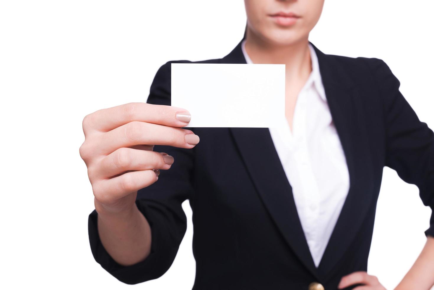 Copy space on her business card. Close-up of young woman in formalwear stretching out her business card while standing isolated on white photo