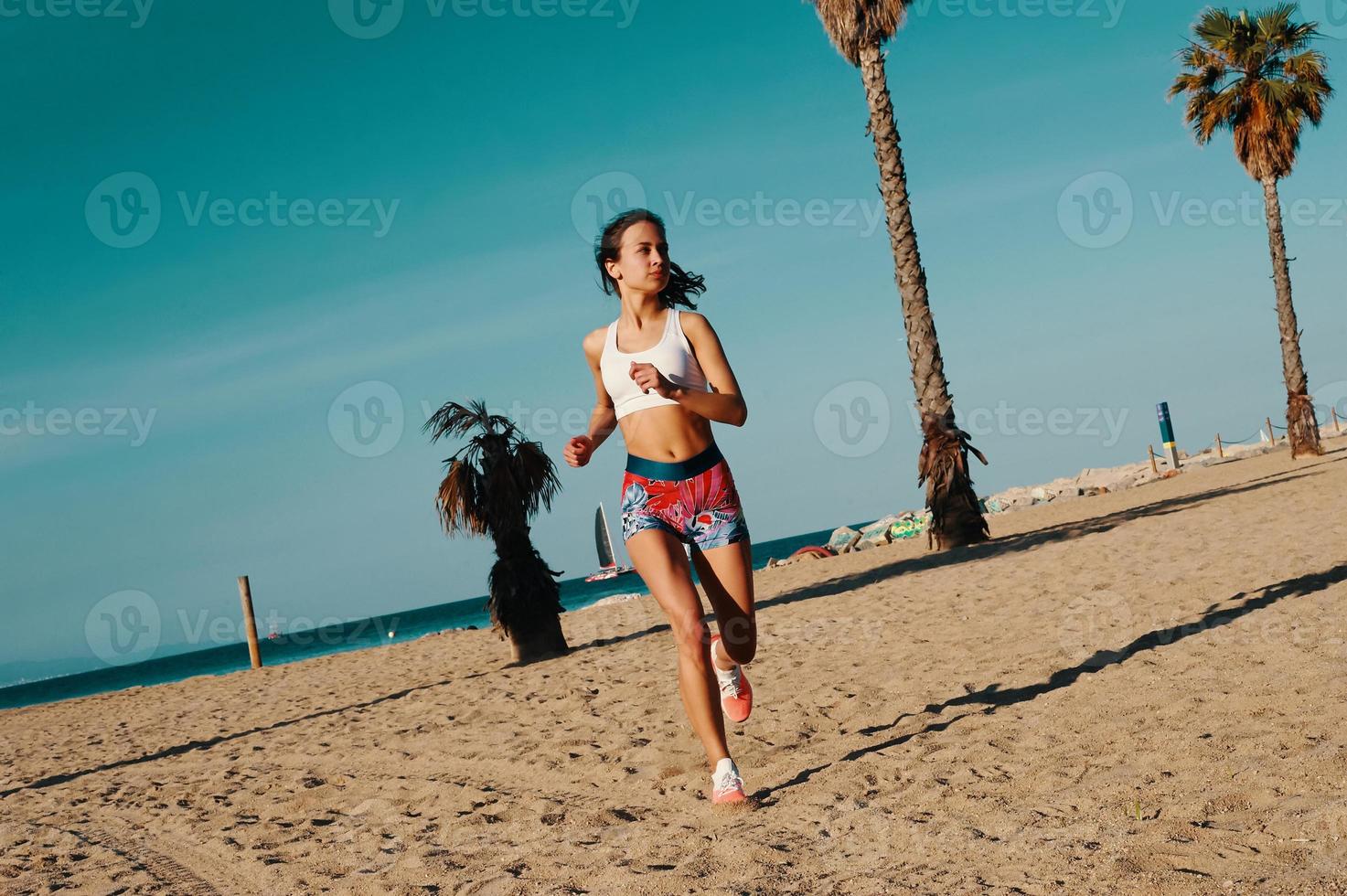 motivada para moldear su cuerpo. toda la longitud de una hermosa joven con ropa deportiva trotando mientras hace ejercicio al aire libre foto