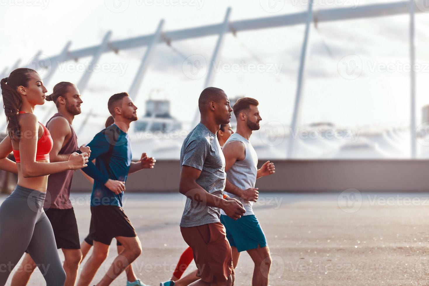 grupo de jóvenes con ropa deportiva corriendo juntos al aire libre foto