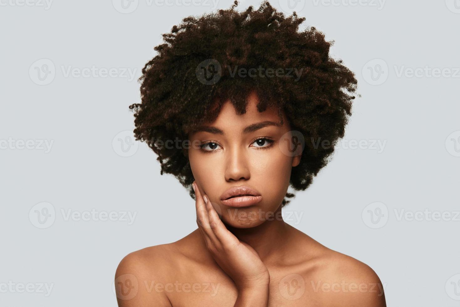 Bored. Upset young African woman looking at camera and making a face while standing against grey background photo