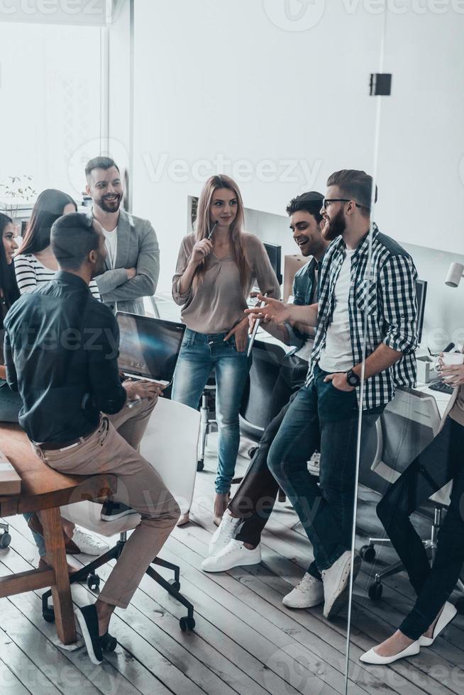 Team working together.  Group of young modern people in smart casual wear discussing something in their office photo