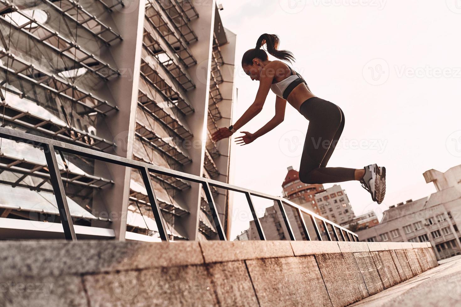 haciendo ejercicio toda la longitud de una joven moderna con ropa deportiva saltando mientras hace ejercicio al aire libre foto