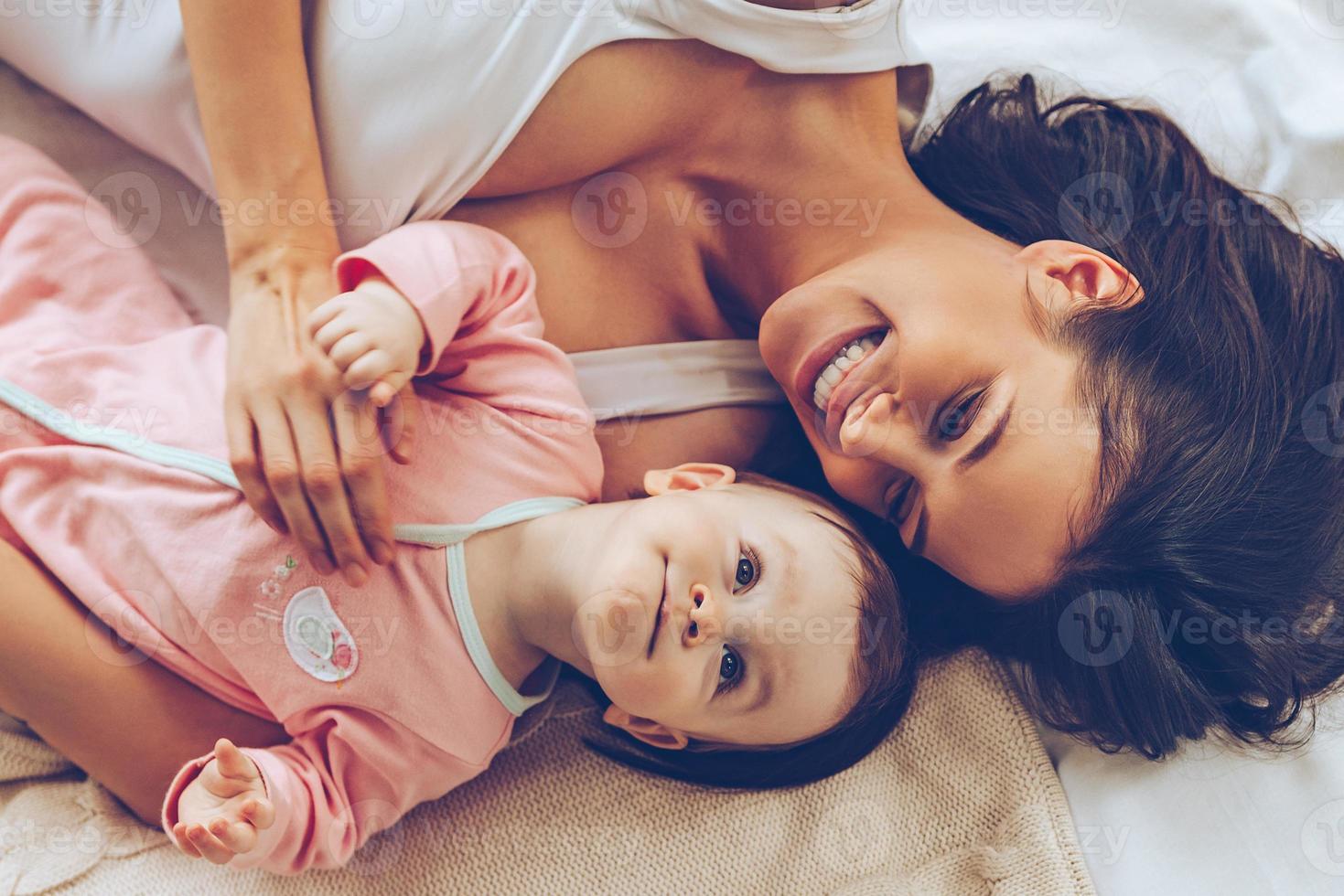 Best daughter ever. Top view of cheerful beautiful young woman lying in bed with her baby girl photo