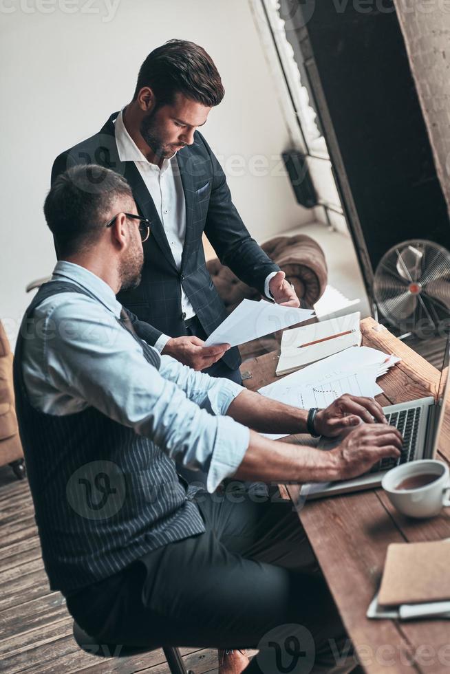 dando consejos de negocios. dos jóvenes modernos en ropa formal trabajando juntos mientras están sentados en el interior foto