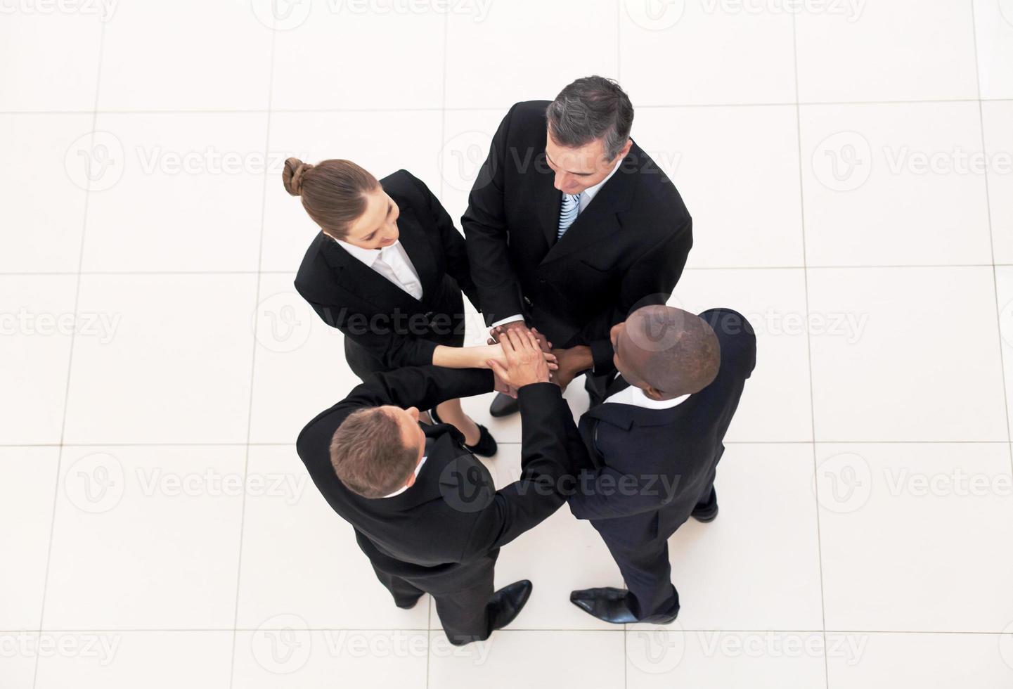 We are team. Top view of four business people in formalwear standing close to each other and holding hands together photo