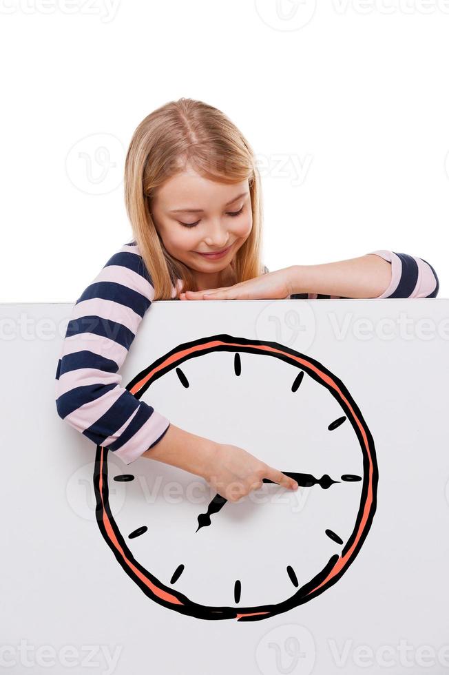 Time goes back. Cheerful girl leaning over white board with clock sketch on it and adjusting arrow while standing against white background photo