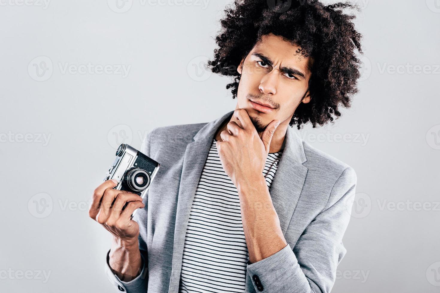 Do you want a photo or not Handsome young African man holding retro styled camera and looking at camera while standing against grey background