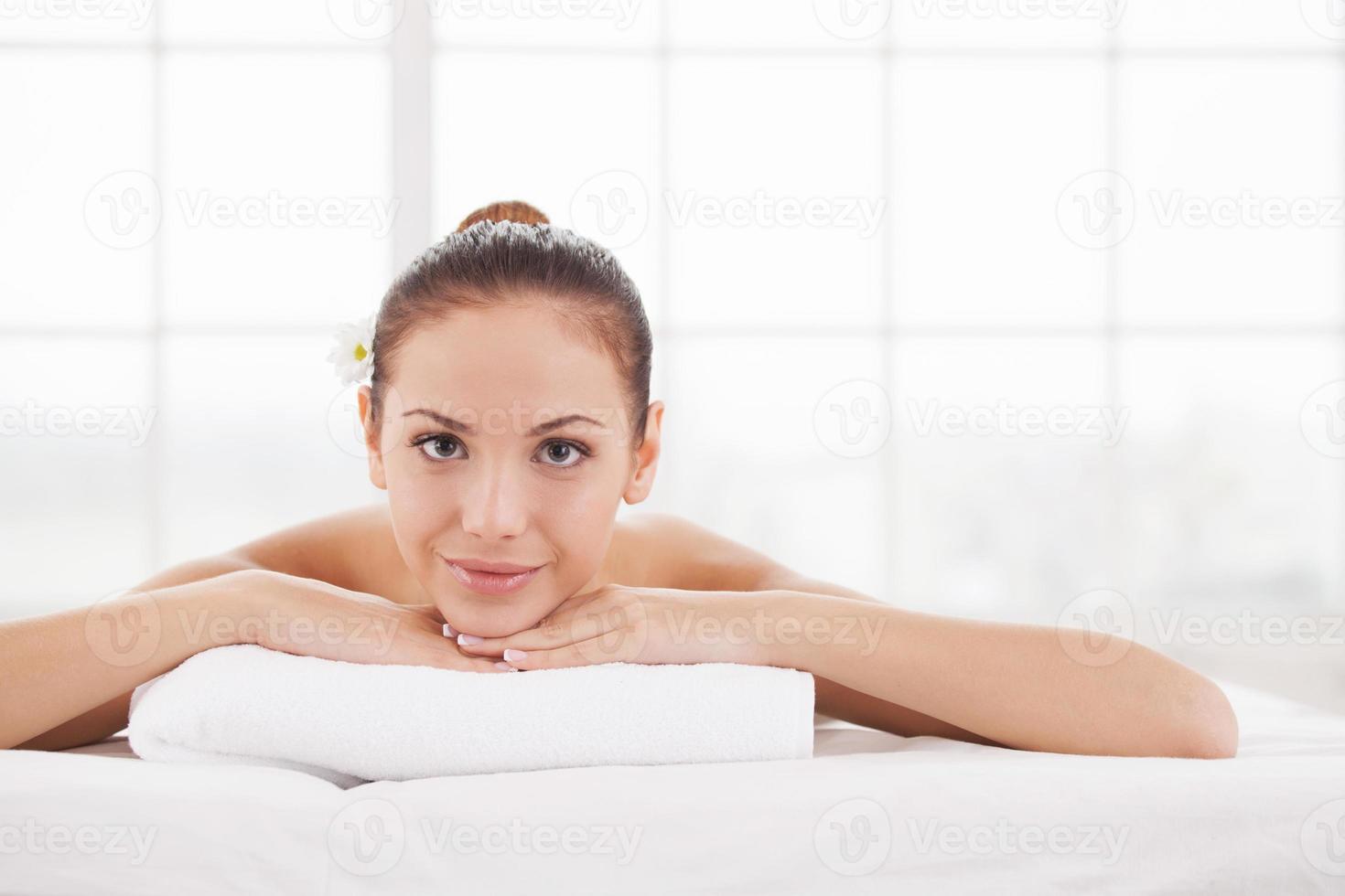 Only good thoughts. Beautiful young woman lying on massage table and looking at camera photo