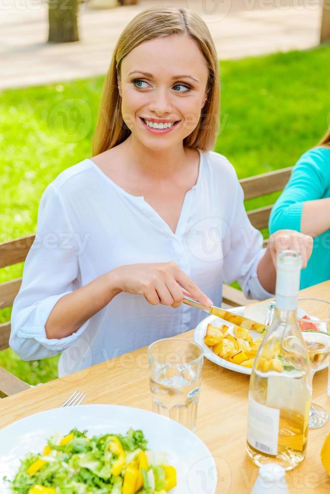 Enjoying dinner and fresh air. Top view of happy young woman enjoying meal while sitting at the dining table outdoors photo
