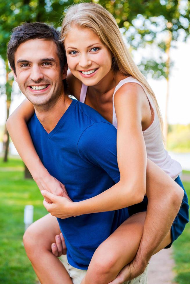 divirtiéndonos juntos. vista en ángulo bajo de una hermosa pareja joven y amorosa parada al aire libre mientras una mujer abrazaba a su novio y sonreía foto