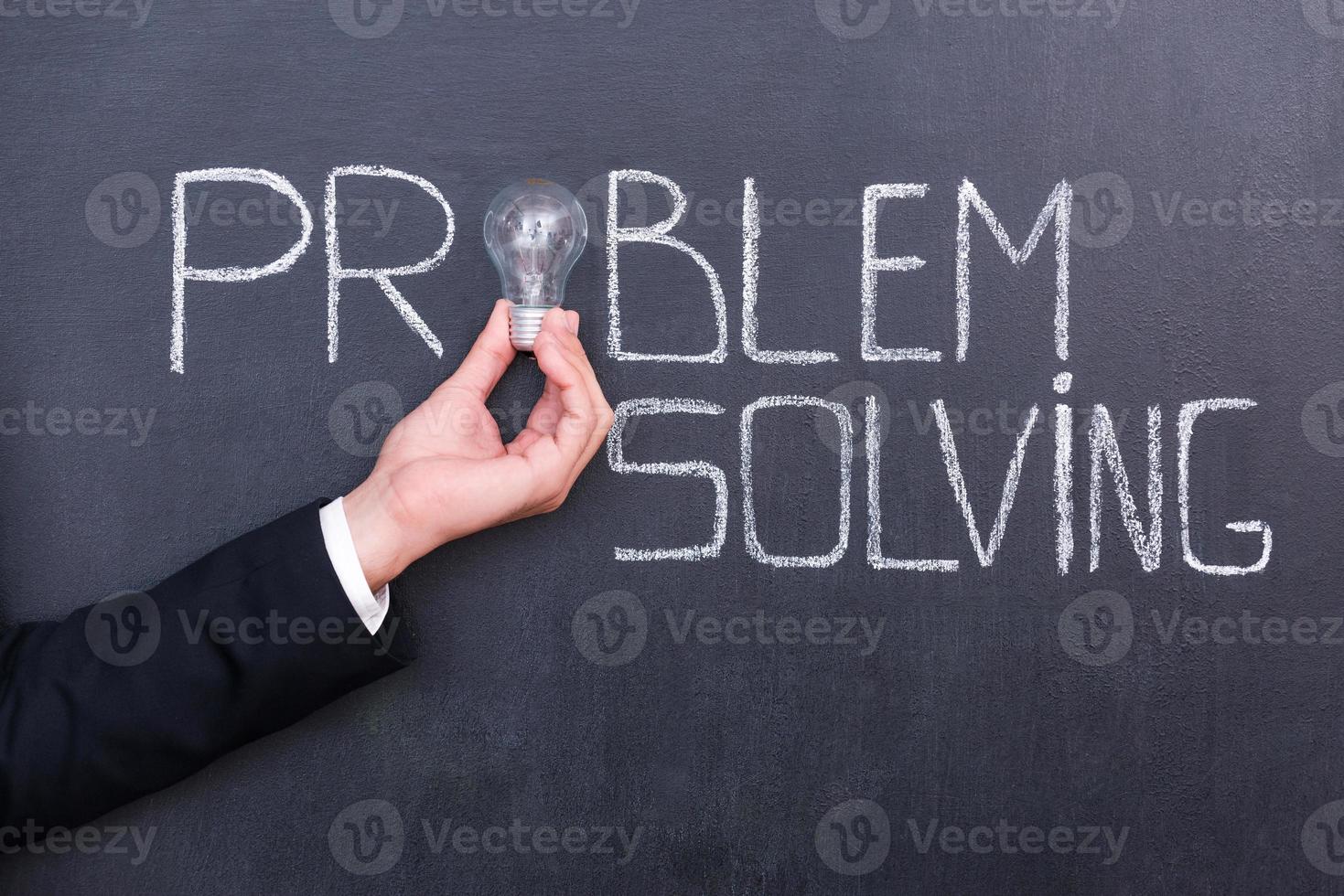 There is no problem. Close-up of human hand holding light bulb in front of chalk drawing on blackboard photo