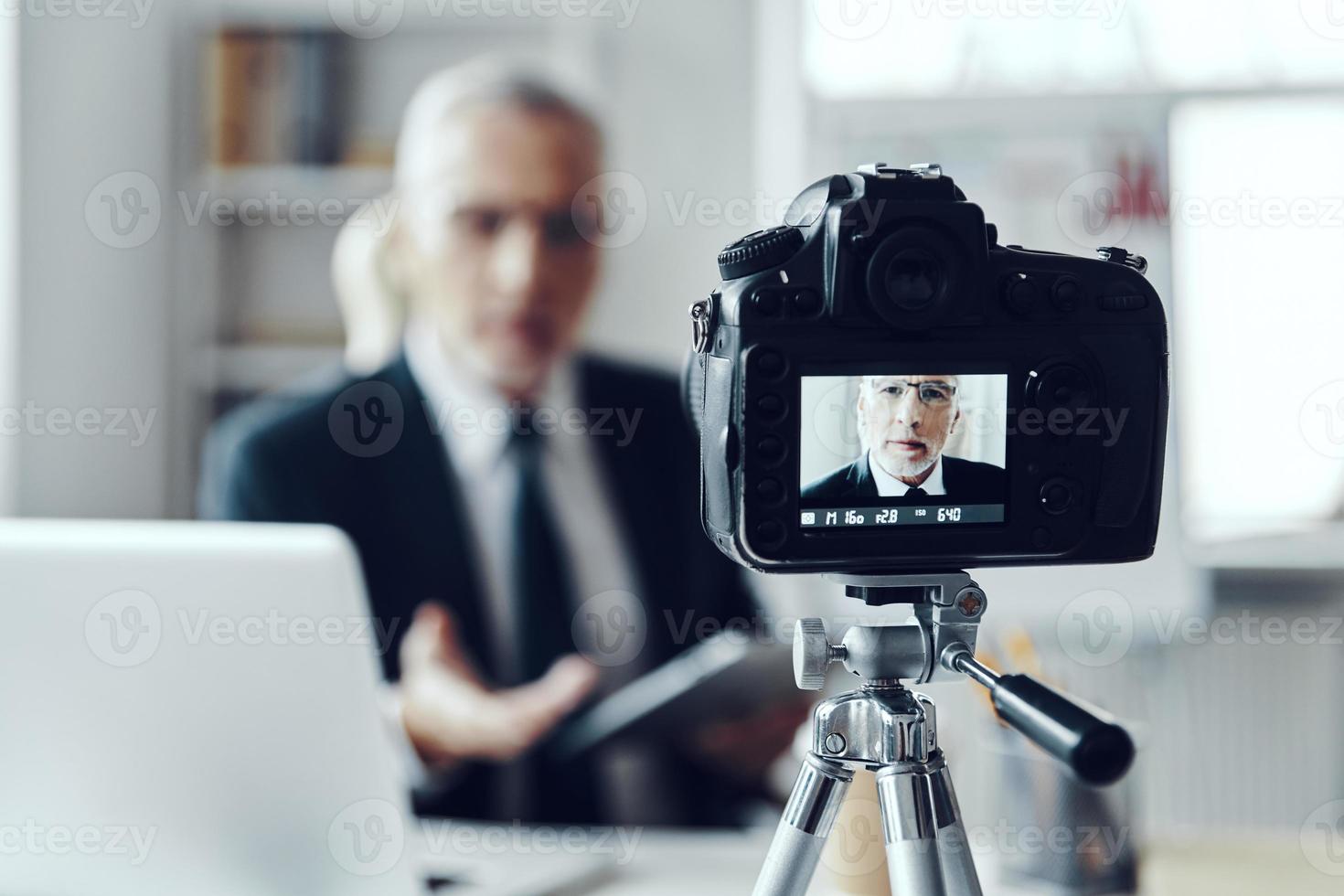 Senior man in elegant business suit using digital tablet while making social media video photo
