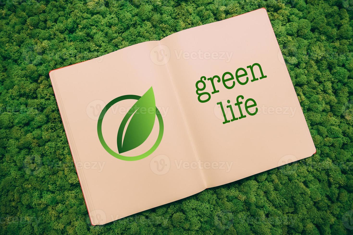 Green life. Top view close-up image of notebook with leaf symbol and text at moss background photo