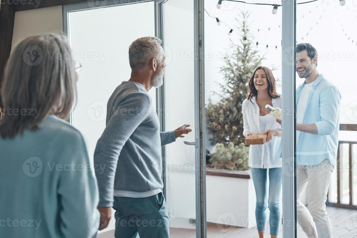 felices padres mayores conociendo a una pareja joven dentro de la casa foto