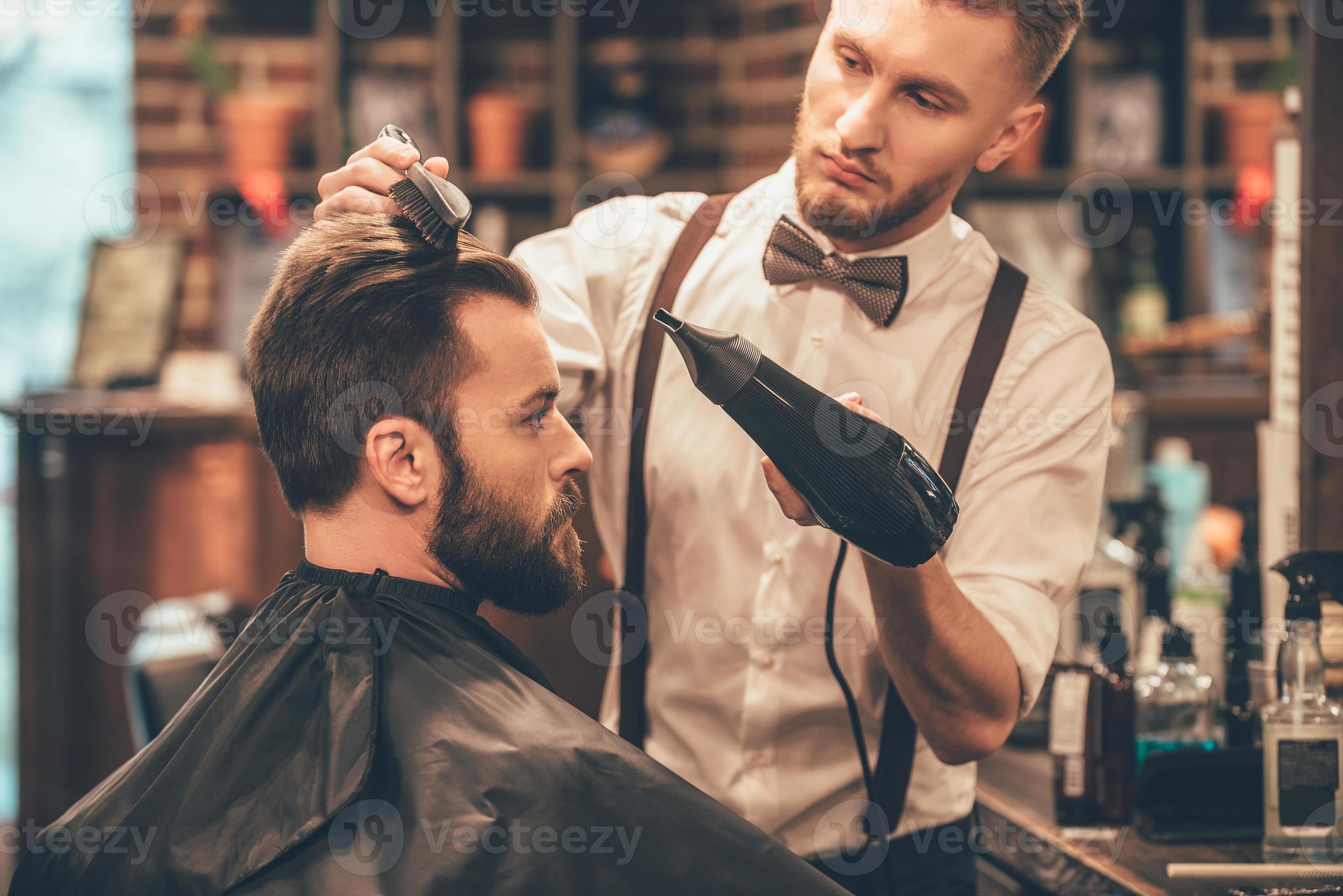 New hairstyle. Side view of young bearded man getting groomed at  hairdresser with hair dryer while sitting in chair at barbershop 13573927  Stock Photo at Vecteezy