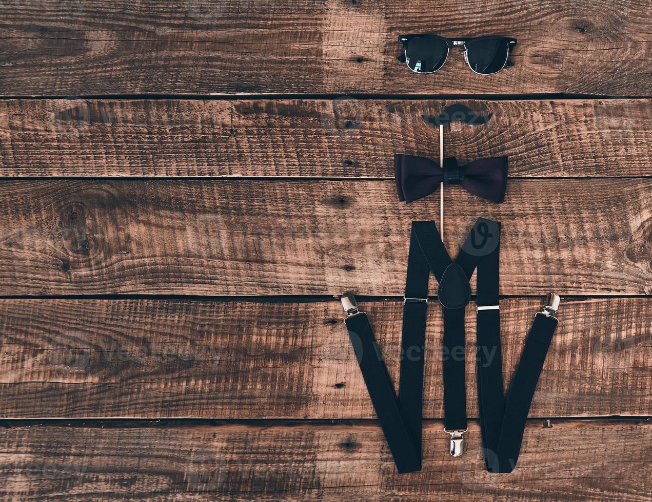 Pure elegance. High angle shot of suspenders, prop, bow tie and eyewear lying on wooden desk photo