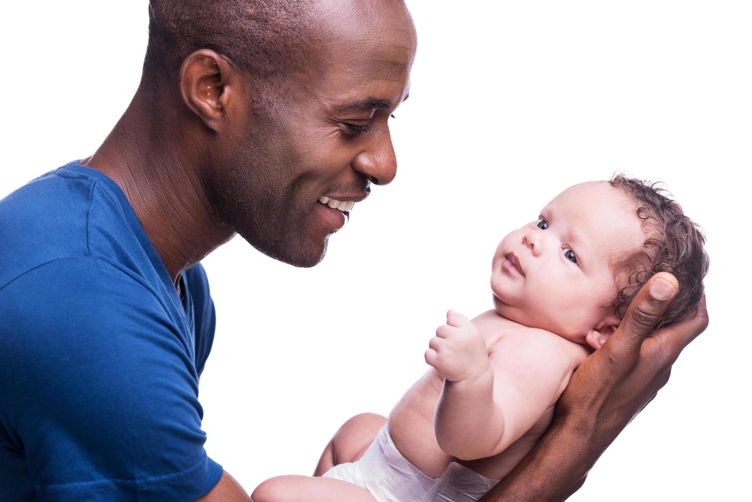 Happy father. Side view of happy young African man holding his little baby and looking at him with smile while standing isolated on white photo