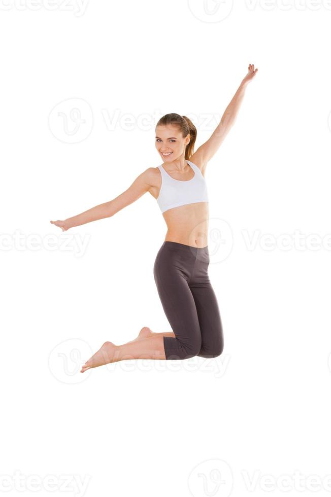 Woman jumping. Beautiful young woman in sports clothing jumping while isolated on white photo