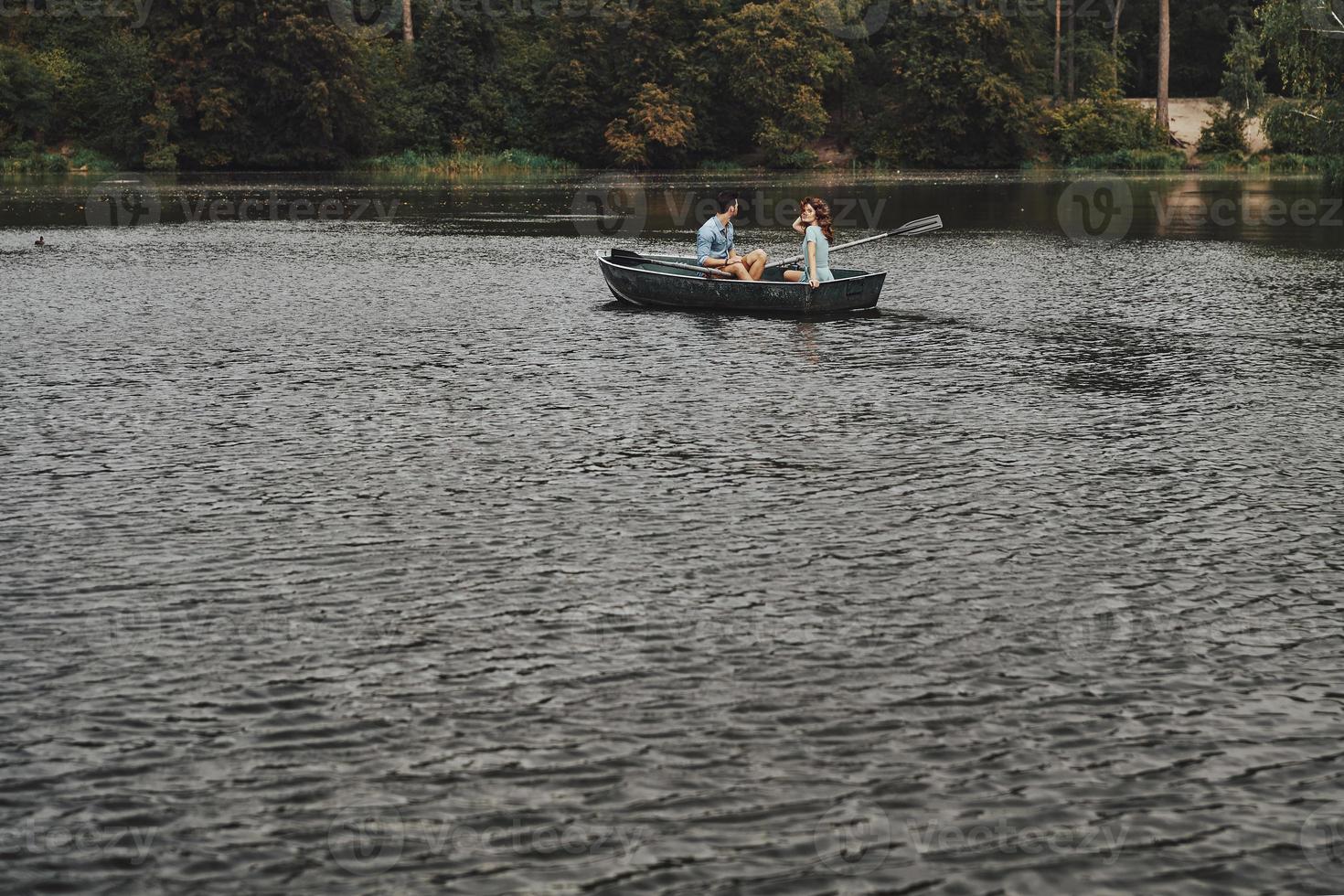 Stress free zone. Beautiful young couple having romantic date while rowing a boat photo