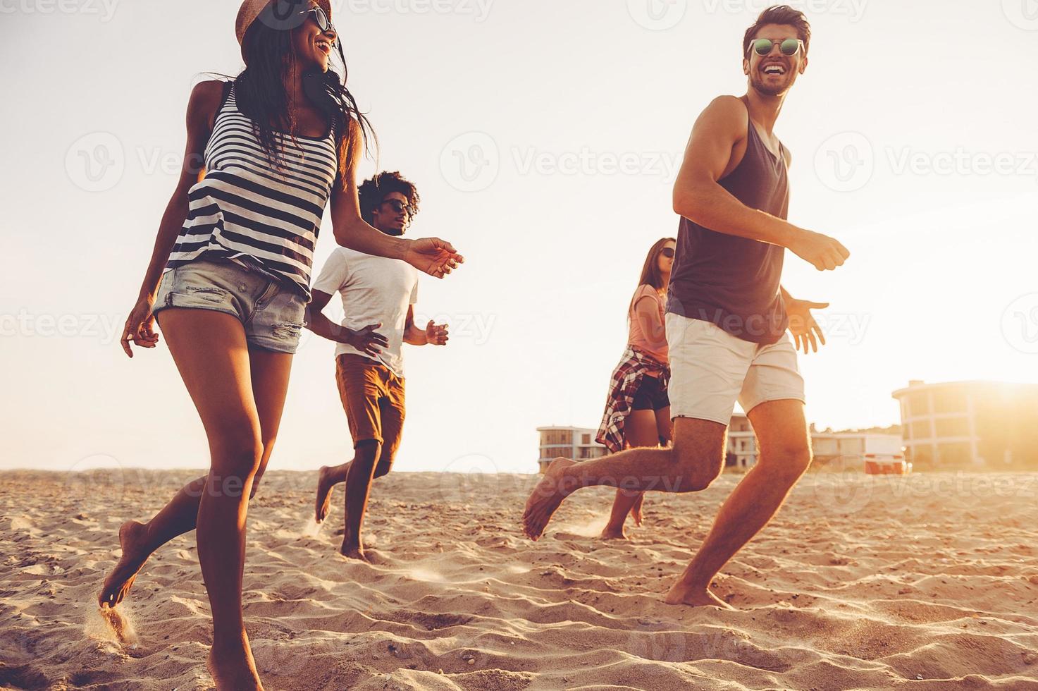 Young evening jog. Group of young cheerful people running by the beach and looking happy photo