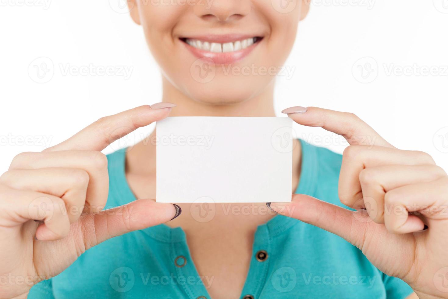 Woman with business card. Cropped image of young woman holding business card in her hand and smiling while standing isolated on white photo