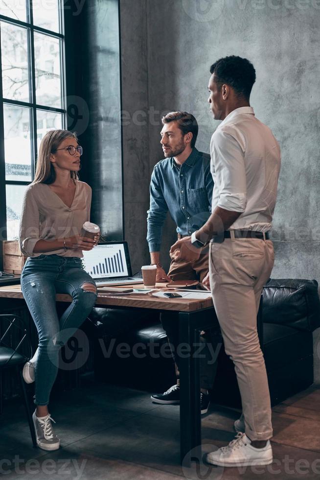 Group of young people in smart casual wear discussing business while working in the office photo