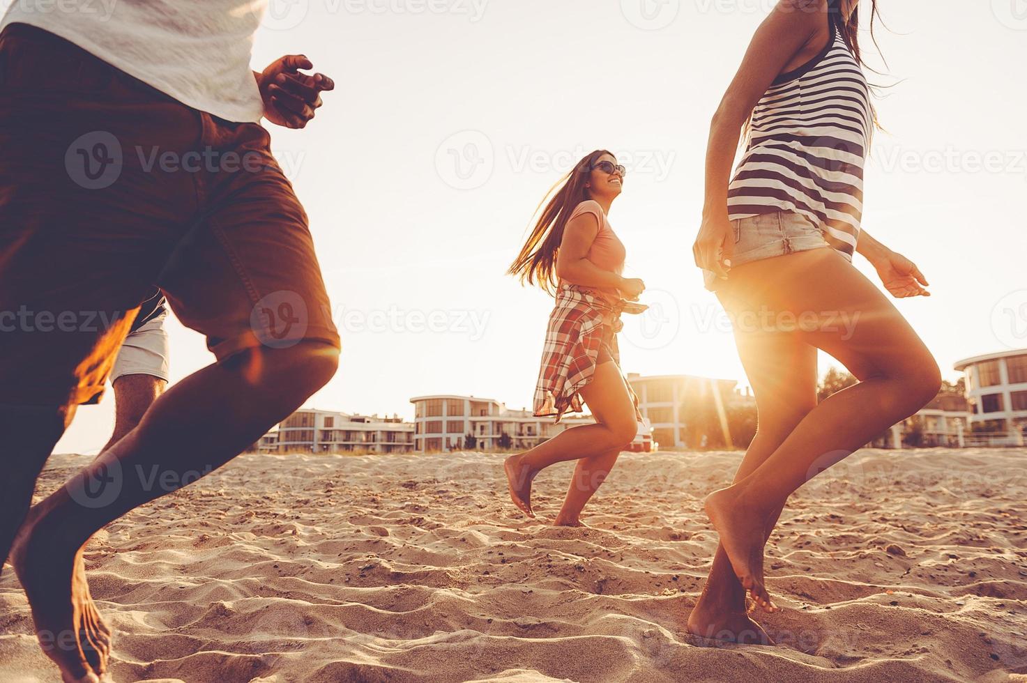 Young and full of energy. Group of young cheerful people running along the beach and looking happy photo