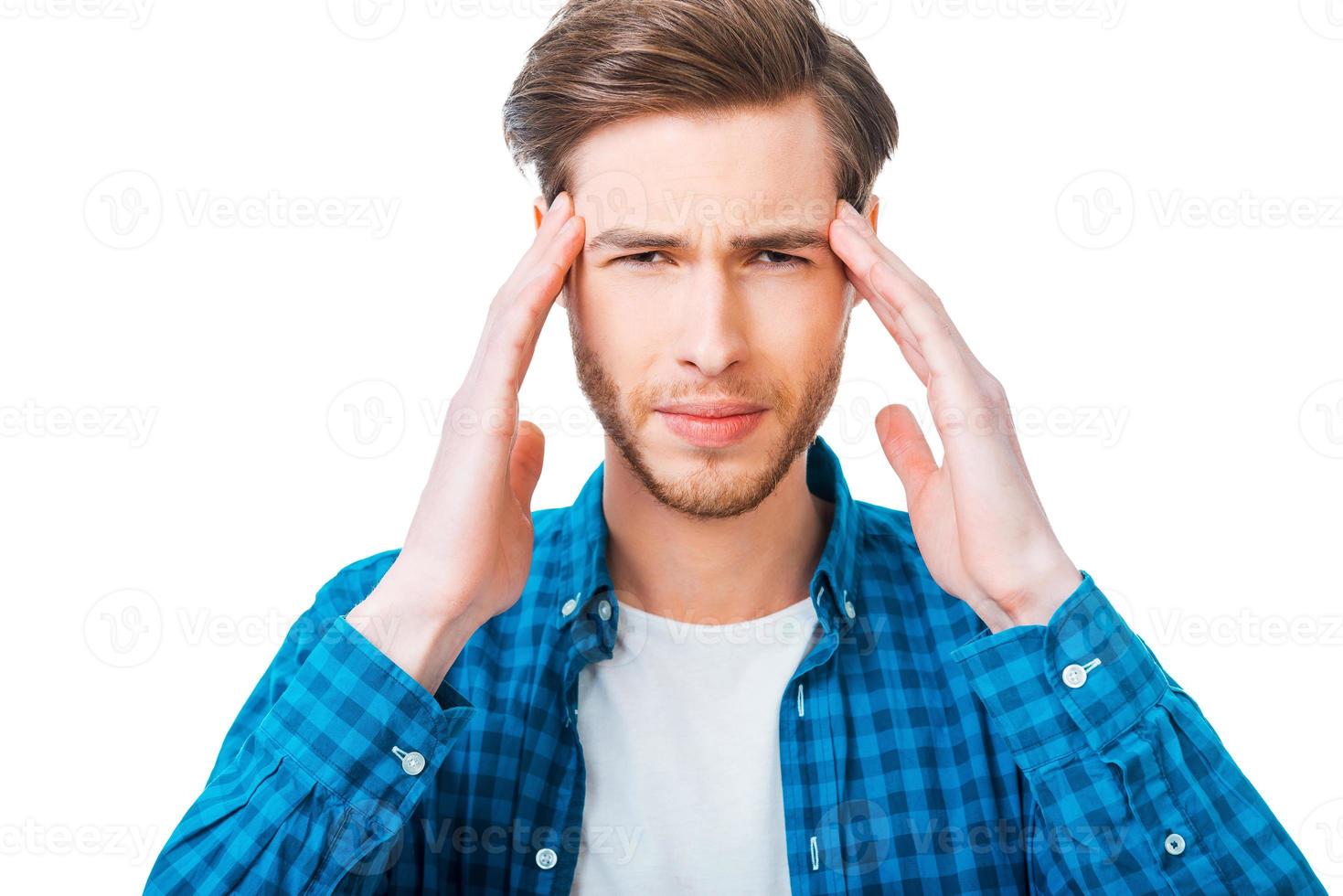 Feeling exhausted. Frustrated young man touching his head while standing against white background photo