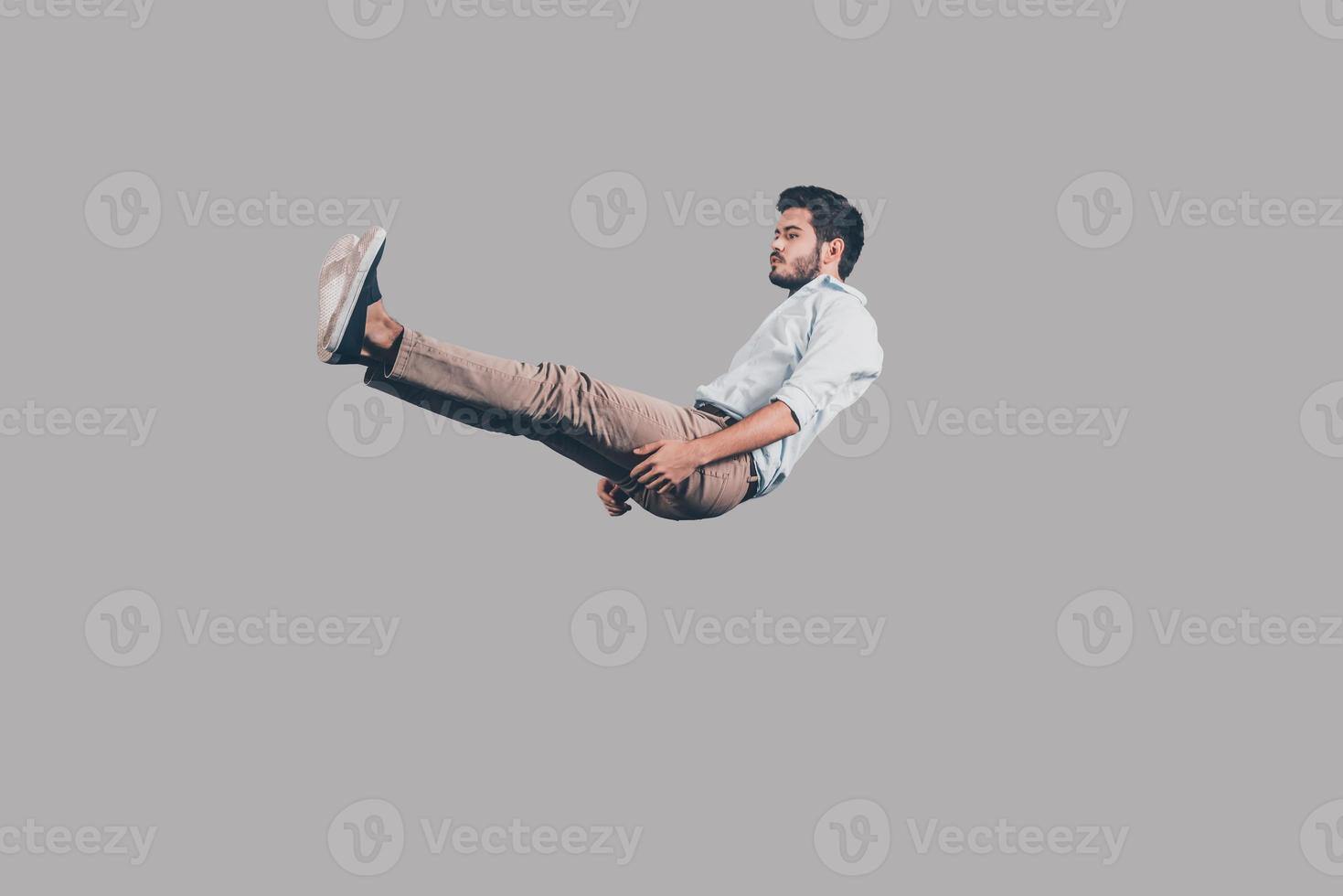 Falling down. Mid-air shot of handsome young man falling against grey background photo