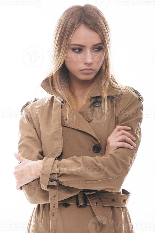 Autumn style. Attractive young woman in coat looking away while standing against white background photo